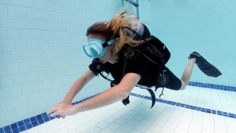 Female scuba diver in full scuba diving equipment hovering in a purpose-built training pool.