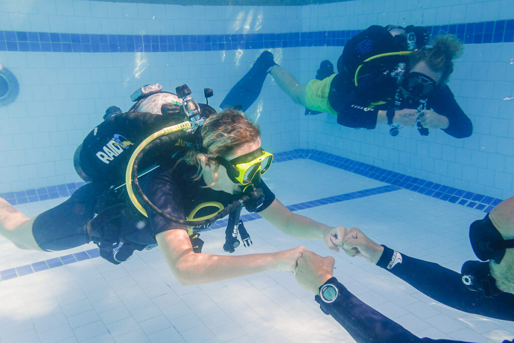 Student divers in a pool learning from an instructor.