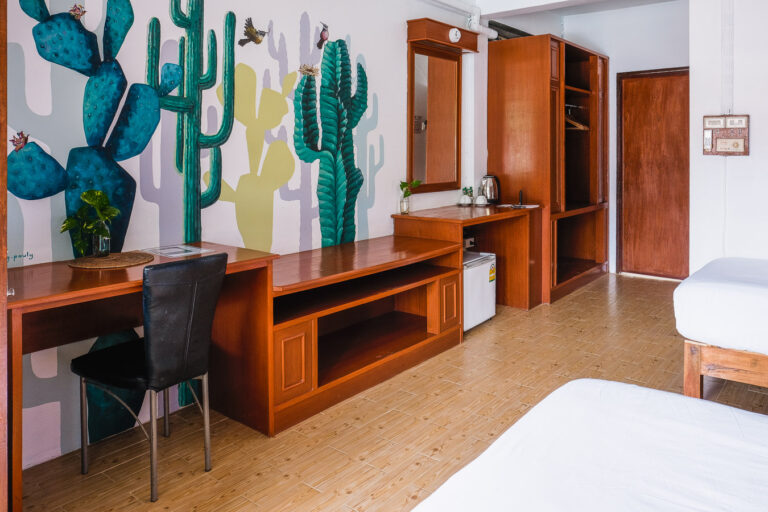Twin beds in a superior room with cactuses painted on the walls.