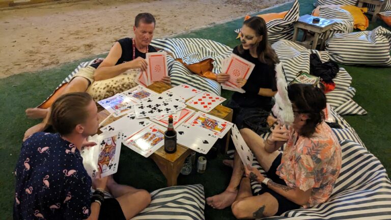 People in Halloween costumes hanging out and playing a giant deck of cards.